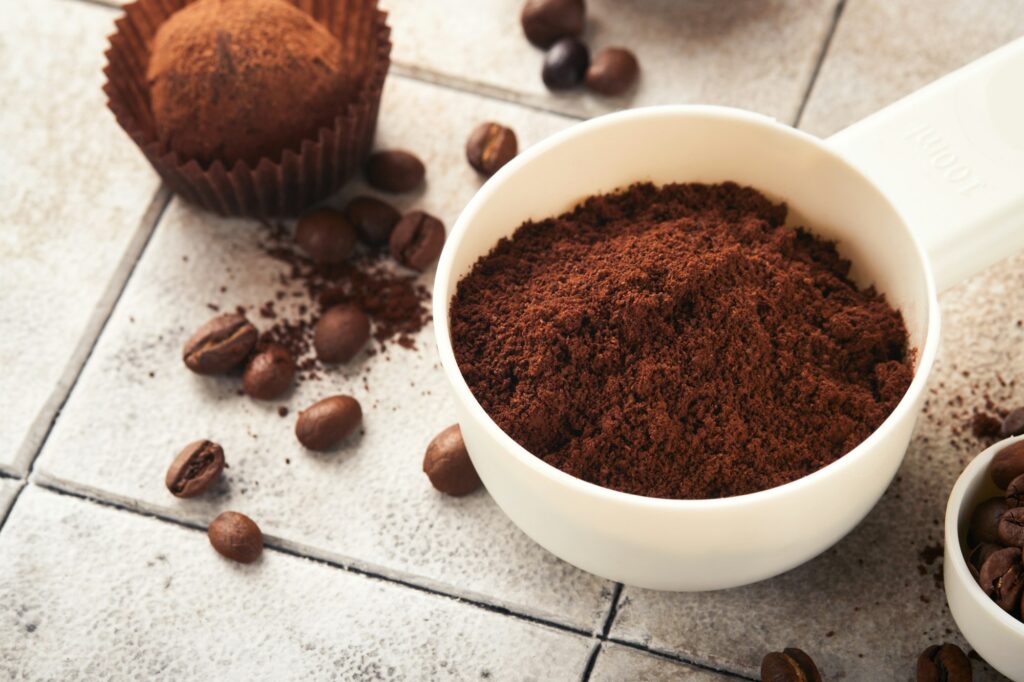 Coffee background. Measuring spoons with ground coffee, beans, cup and sweet chocolate truffles on o